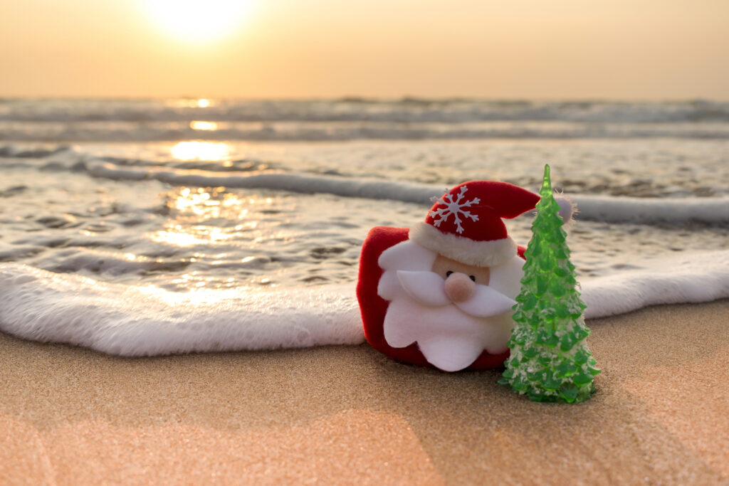 Decorative Santa and Christmas tree near the ocean waves.